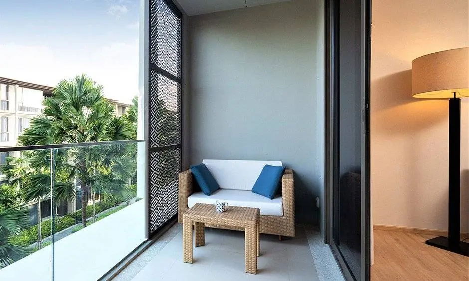 Bangalore bedroom with balcony overlooking nature, small chair and table, designed by Olangana Designs expert