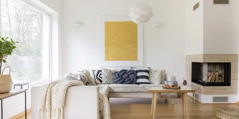 Minimalist white living area with L-shaped seating and fireplace