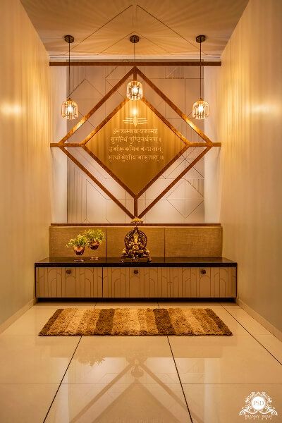 Elegant modern puja room interior design by Olangana in Bangalore, featuring a golden diamond-shaped back panel with Sanskrit inscription, a brass Ganesh idol, stylish pendant lights, and custom storage cabinetry.