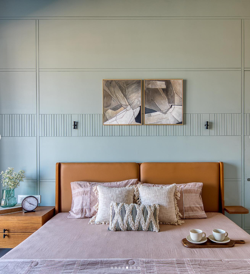 Modern bedroom interior design by Olangana Design in Bangalore, featuring a tan leather headboard, textured pillows, light green paneled wall with fluted details, and abstract art.