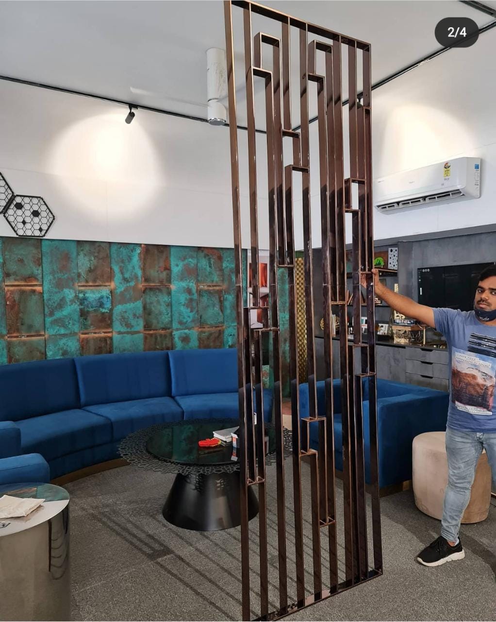 Modern living room interior with a blue curved sofa, elegant metal partition, and textured wall panel, expertly designed by Olangana Design in Bangalore.