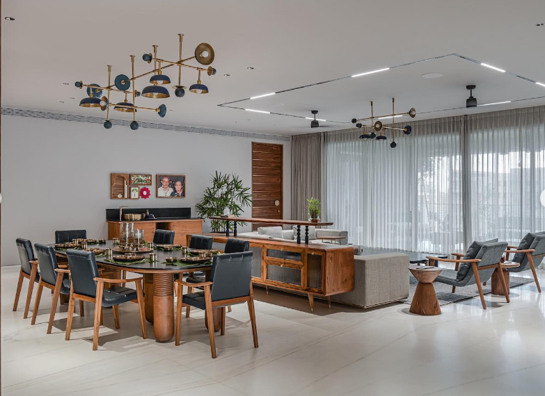 Elegant open-plan living and dining interior design by Olangana Design in Bangalore, featuring modern wooden furniture, a stylish chandelier, and ample natural light.