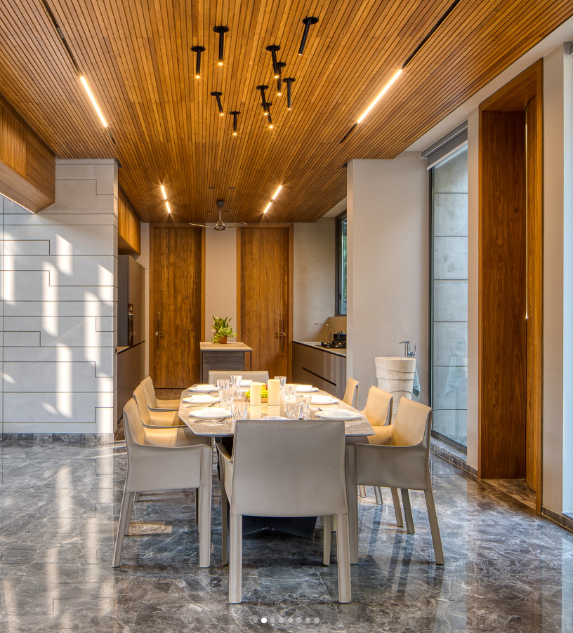 Modern dining room interior design by Olangana Design, featuring a striking wooden ceiling, elegant marble floor, and sophisticated dining set in a Bangalore residence.