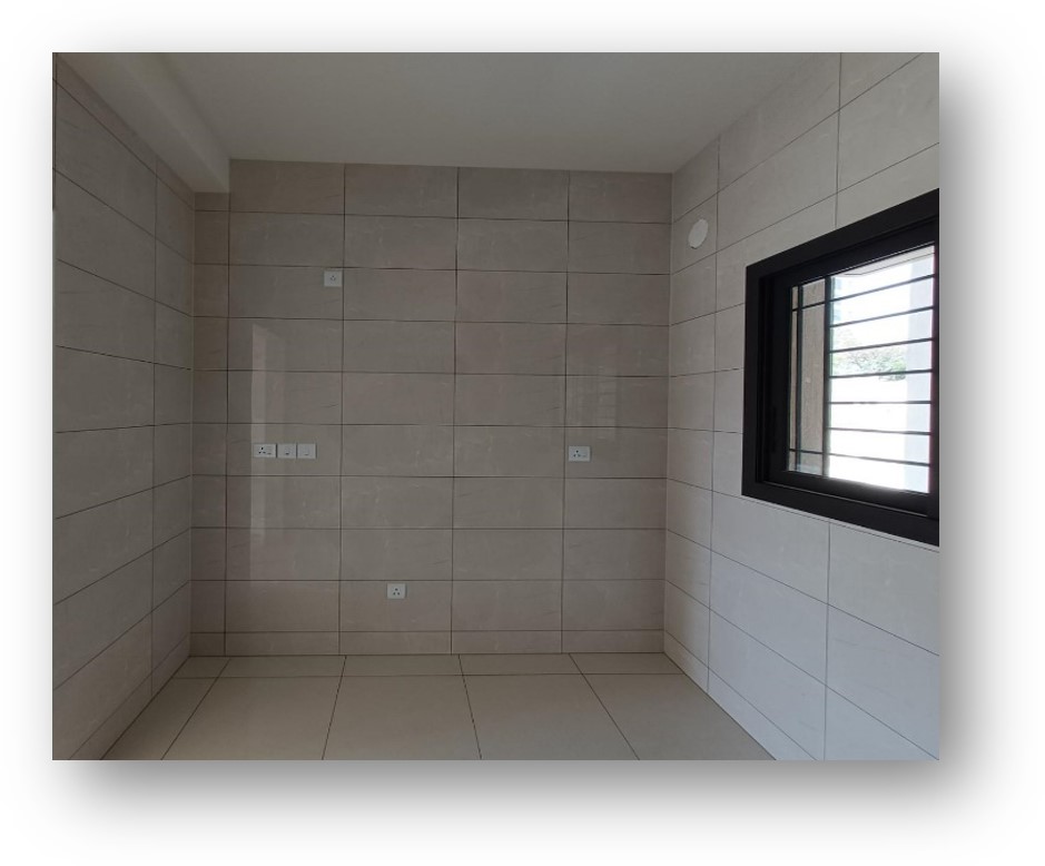 Empty room with light beige tiled walls and floor, black-framed window, and electrical points, a site ready for bespoke interior design transformation by Olangana Design in Bangalore.