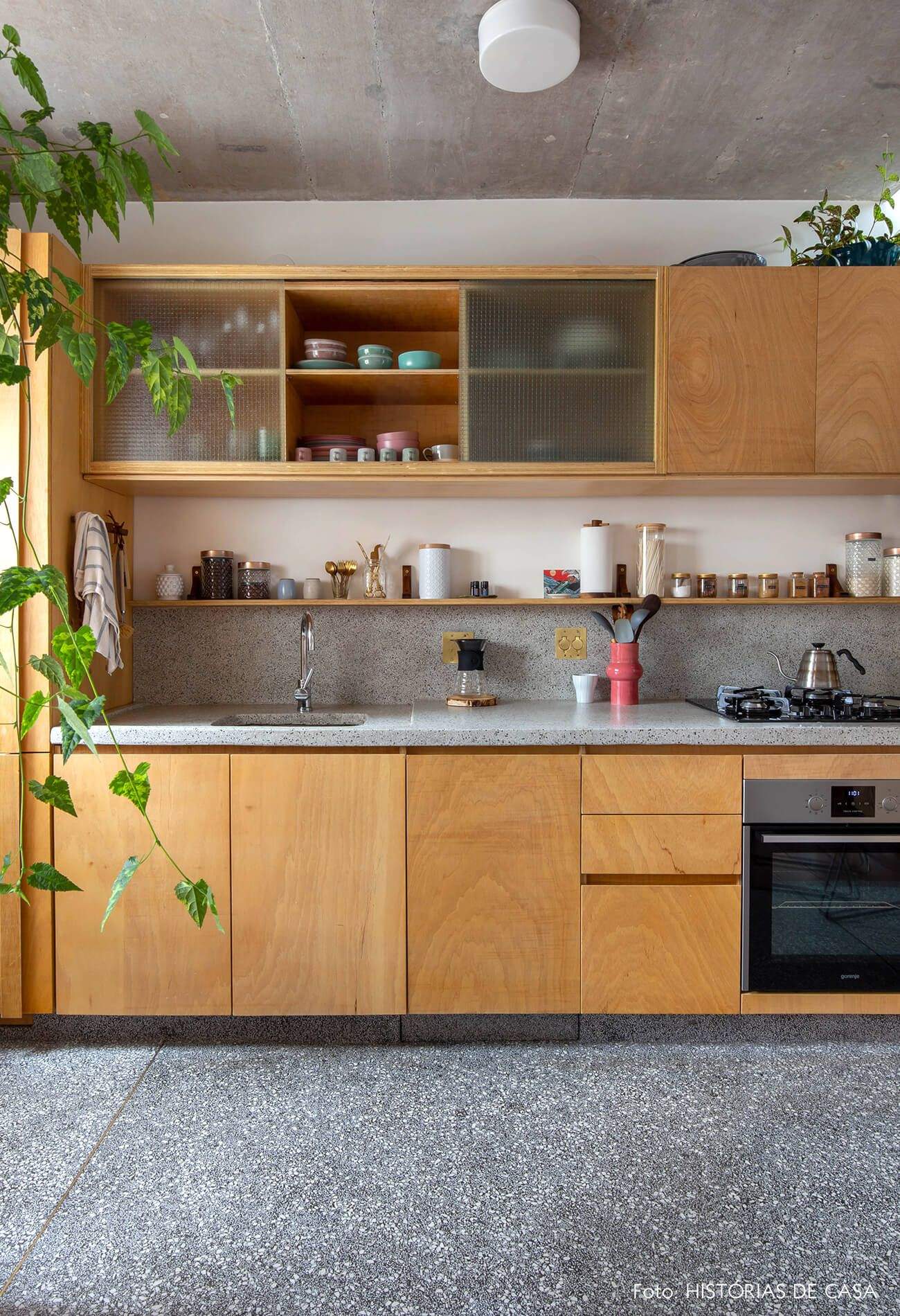 Elegant kitchen interior design by Olangana in Bangalore, featuring light wood cabinetry, reeded glass doors, terrazzo countertops, and a vibrant plant accent.