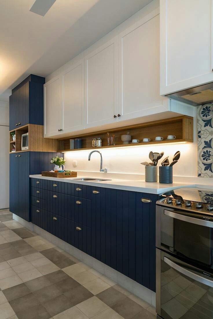 Modern kitchen interior design by Olangana in Bangalore, featuring stylish navy blue and white cabinetry, warm wood open shelving, and a chic patterned backsplash.