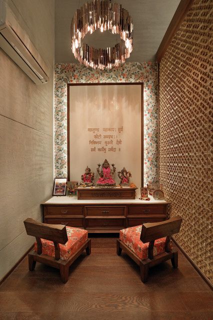 Serene puja room interior design by Olangana in Bangalore, featuring a modern circular chandelier, floral accent wallpaper, a traditional wooden altar with deities, and elegant low seating with patterned cushions.