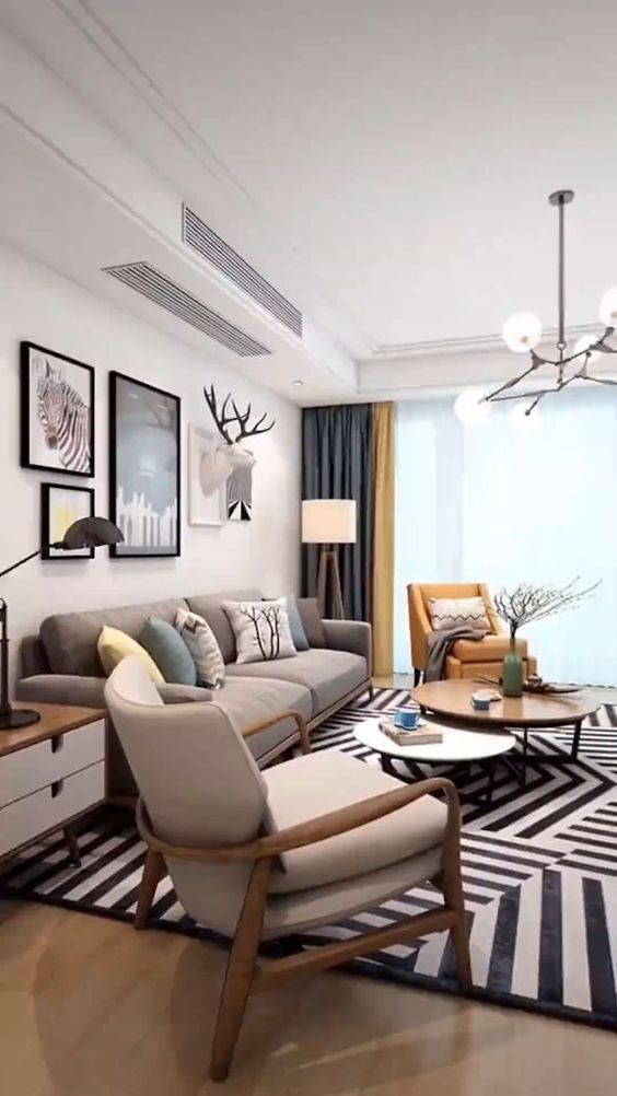 Modern living room interior design by Olangana in Bangalore, featuring a grey sofa, yellow accent chair, geometric rug, contemporary wall art, and elegant lighting.