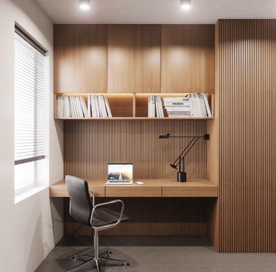 Elegant home office Interior Design by Olangana in Bangalore, featuring warm natural wood slatted walls, integrated desk, and minimalist shelving with subtle LED and task lighting for a productive environment.