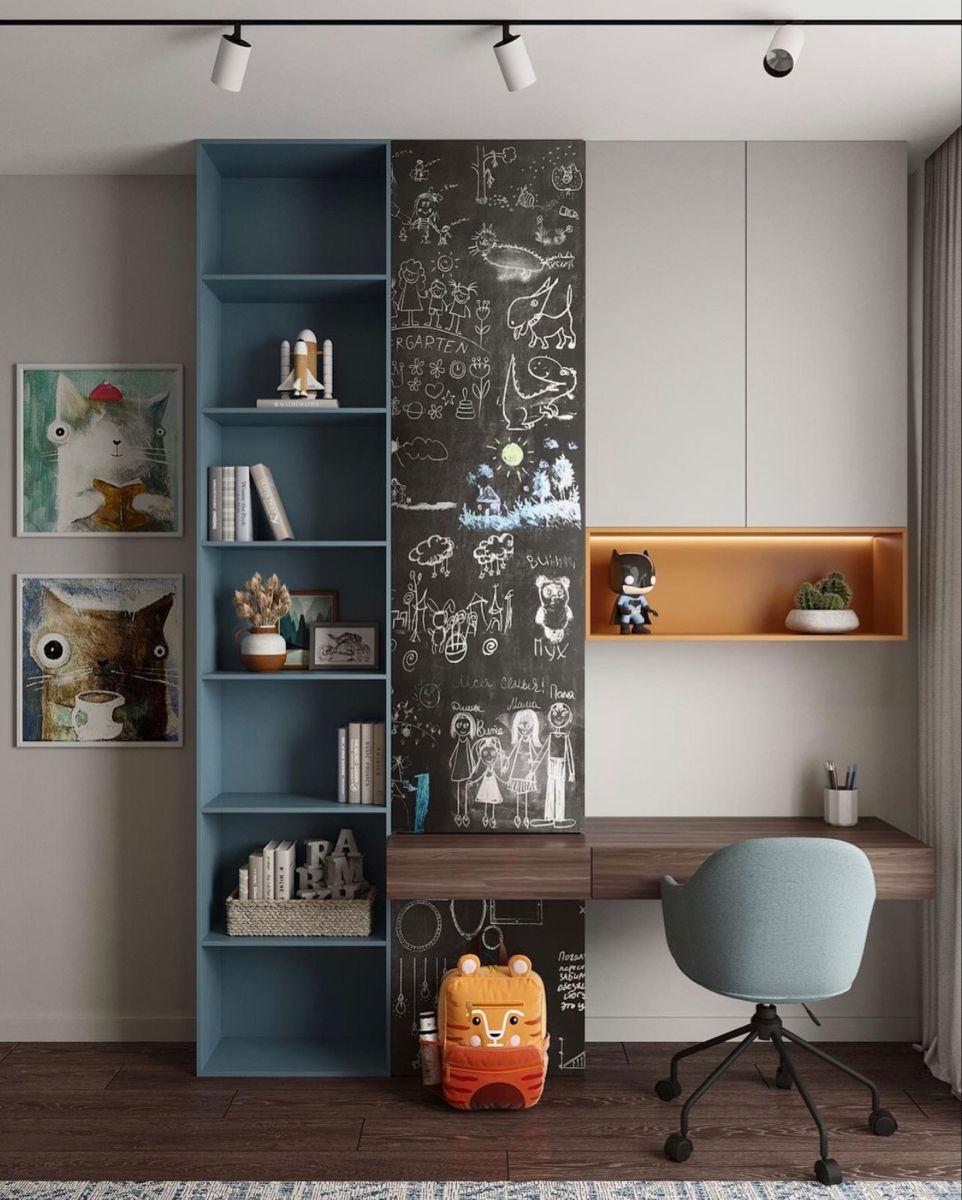 A vibrant and functional children's study area featuring a striking blue bookshelf, an engaging chalkboard wall with whimsical drawings, a modern floating wooden desk, and a comfortable light blue ergonomic chair, expertly designed by Olangana for inspiring Interior Design in Bangalore.