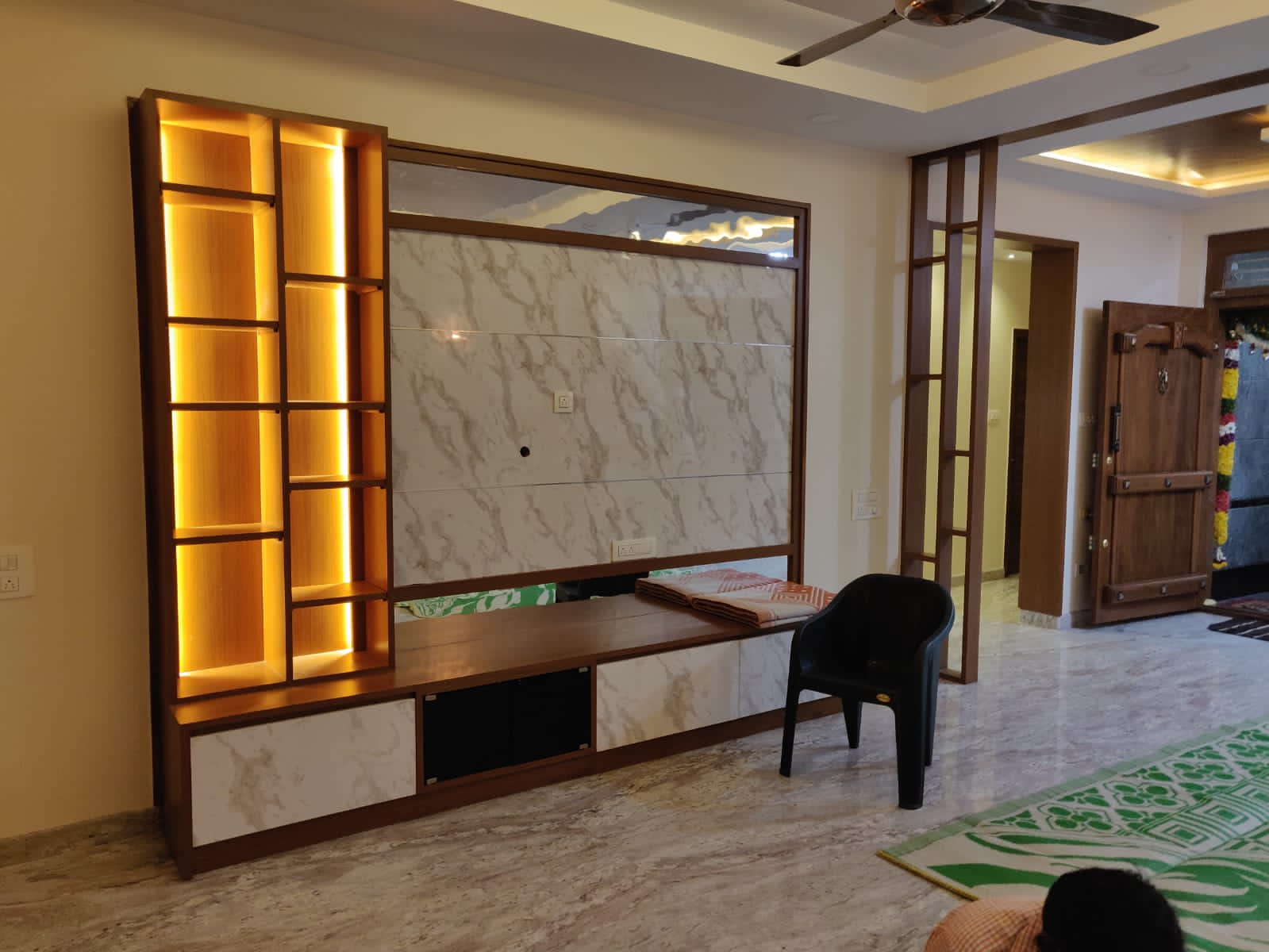 Elegant modern TV unit with warm illuminated shelving and marble-effect panel, showcasing Olangana's exquisite Interior Design in Bangalore.