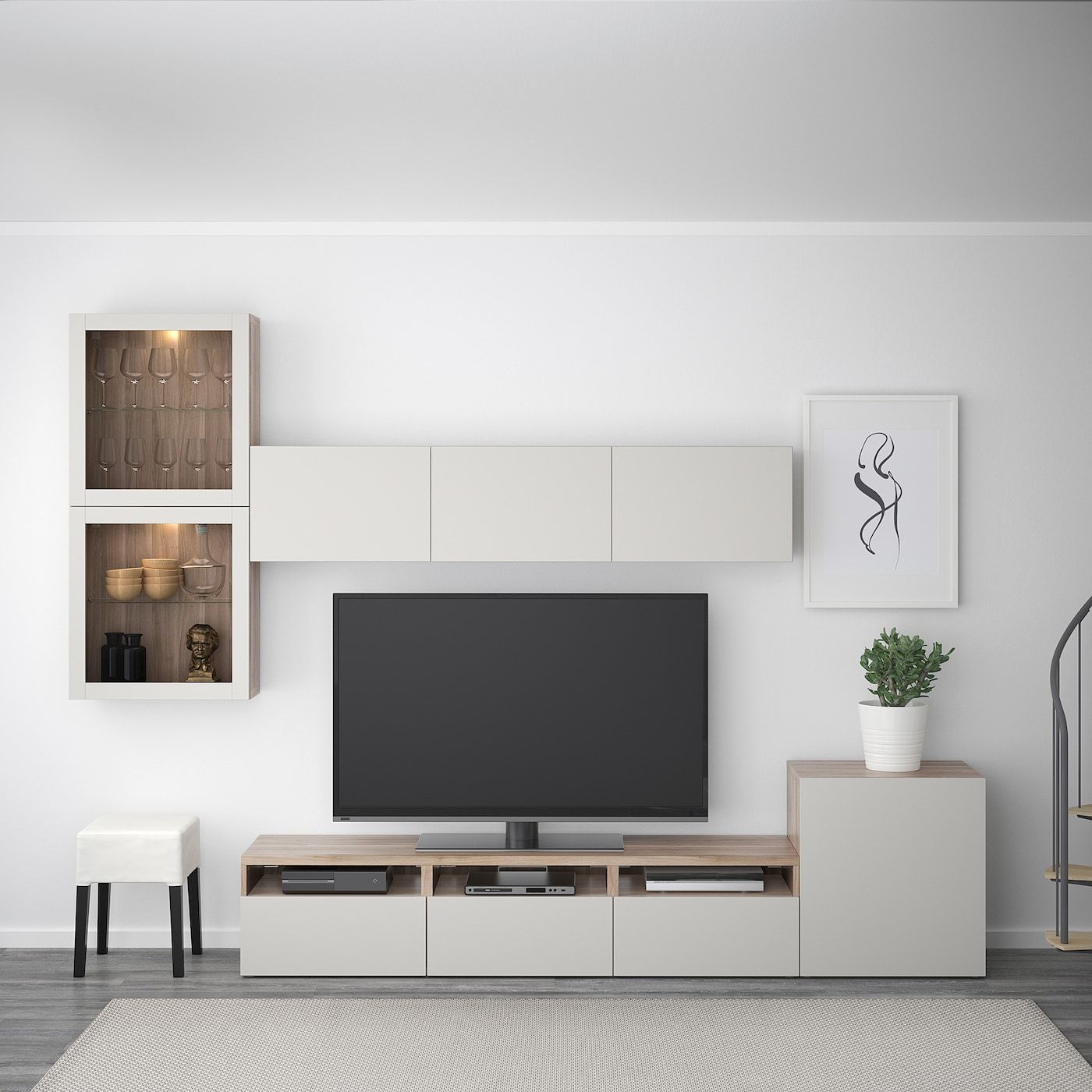 A sleek, modern living room media unit designed by Olangana, featuring a light wood and neutral-toned floating TV console with integrated storage, wall-mounted display cabinets showcasing glassware with warm accent lighting, and minimalist decor. This elegant Interior Design solution enhances functionality and style in homes across Bangalore.