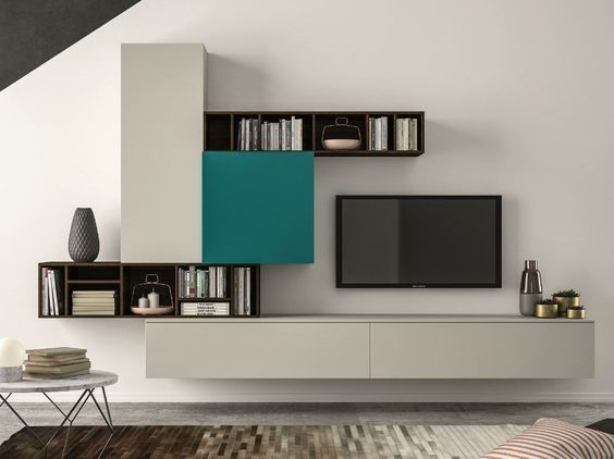 Modern living room Interior Design by Olangana in Bangalore, featuring a sophisticated wall unit with light beige, dark wood, and a vibrant teal accent panel, complete with floating shelves and a TV. This design showcases contemporary elegance.