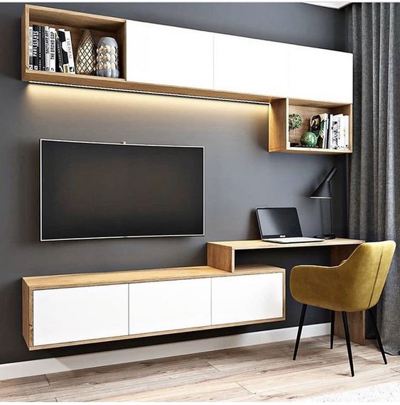 A sleek modern living room and home office setup by Olangana Design, featuring a wall-mounted TV, floating wood and white cabinets, an integrated desk, and a vibrant mustard yellow accent chair. This contemporary Interior Design showcases functional elegance in Bangalore.
