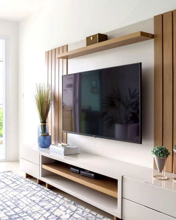A modern and elegant TV unit featuring white cabinetry, warm wood paneling, and minimalist decor, showcasing Olangana Design's expertise in contemporary Interior Design in Bangalore.