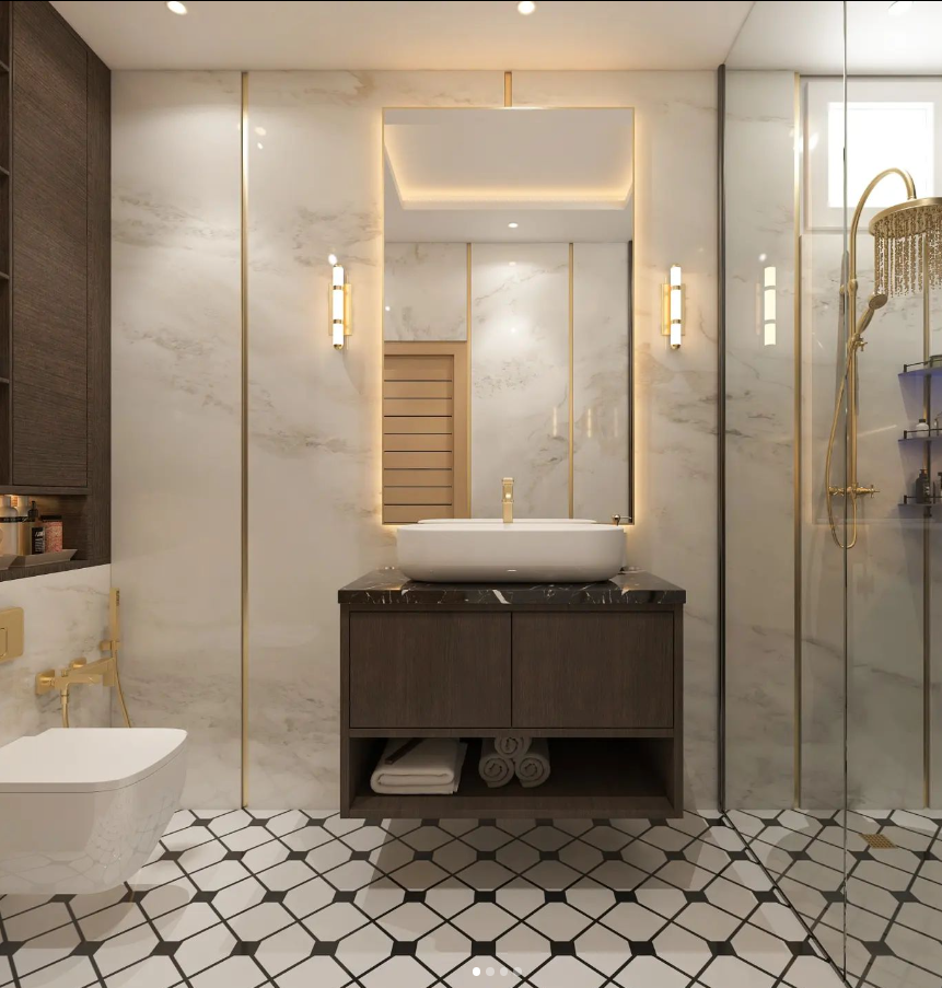 Luxurious modern bathroom interior design by Olangana in Bangalore, featuring white marble walls with elegant gold accents, a dark wood floating vanity with a white basin, a sleek backlit mirror, and a striking black and white geometric patterned floor. Gold fixtures, including a rain showerhead and stylish sconces, elevate the aesthetic, showcasing premium Olangana Design.