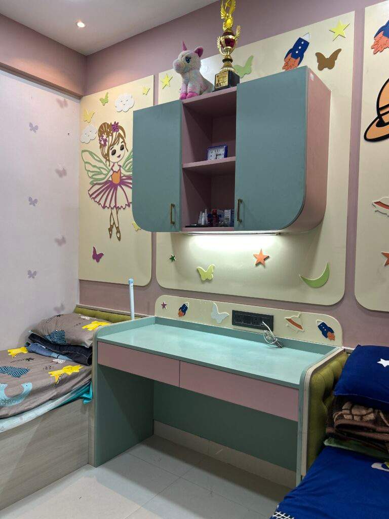 Children’s bedroom with two beds and a shared study table with wall rack lighting in a Bangalore home designed by Olangana Design’s.