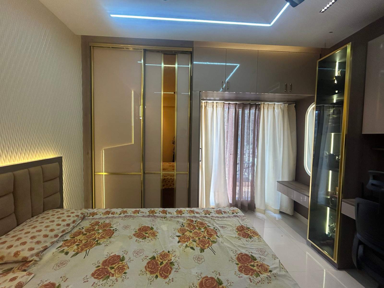 Contemporary master bedroom design with integrated work desk, overhead storage cabinets, and sleek wardrobe finish by Olangana Design’s.
