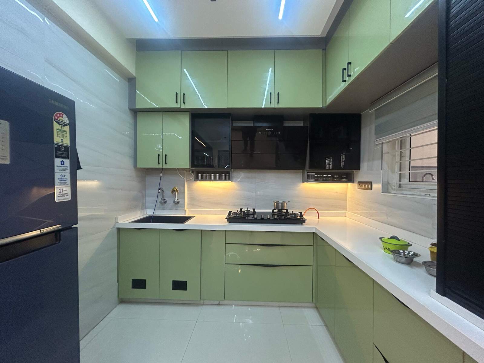 Green modular kitchen storage cabinet with rolling shutter unit in Bangalore home by Olangana Design’s.