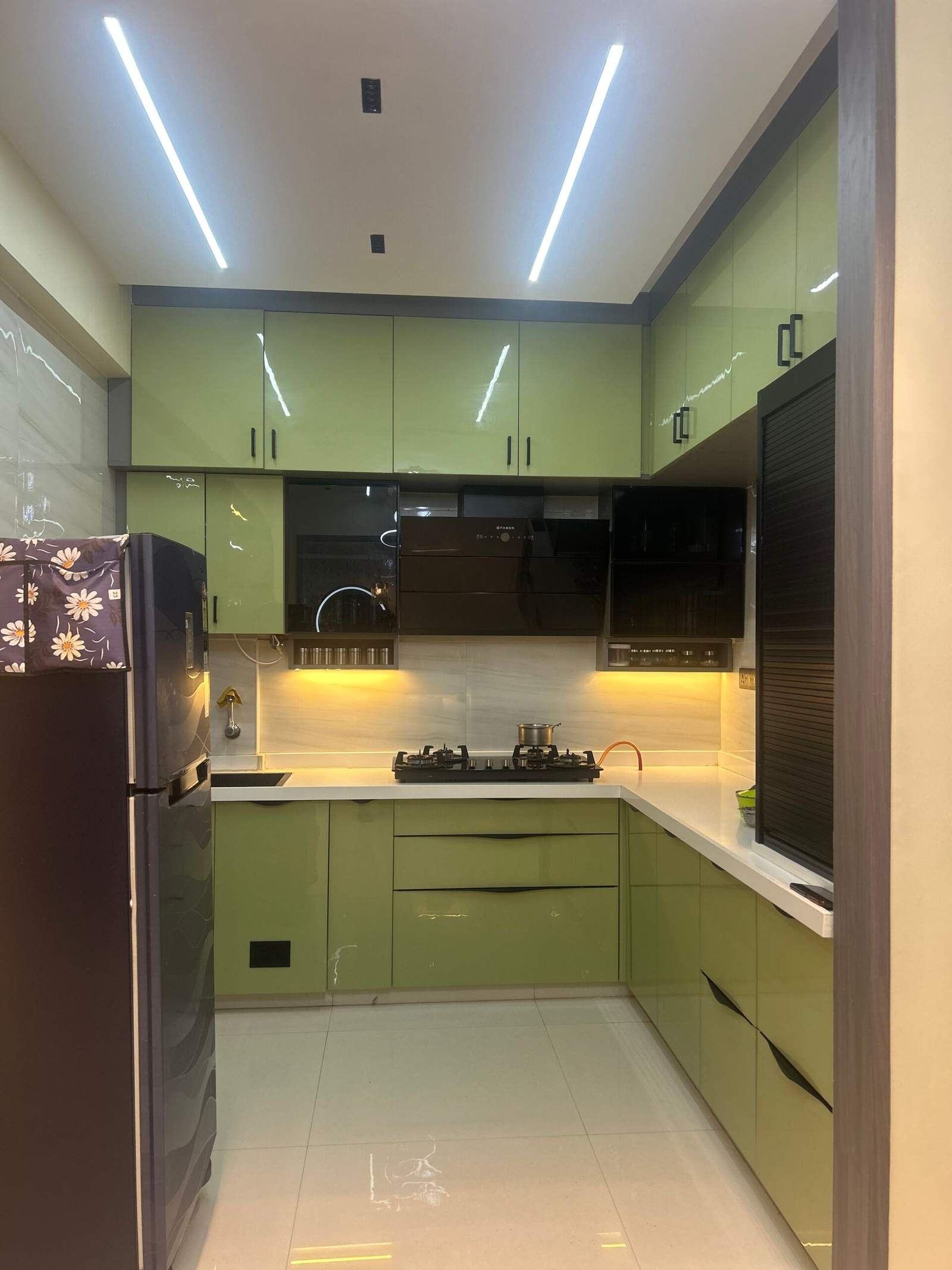 Modular kitchen with green finish cabinets and rolling shutter rack in Bangalore by Olangana Design’s.