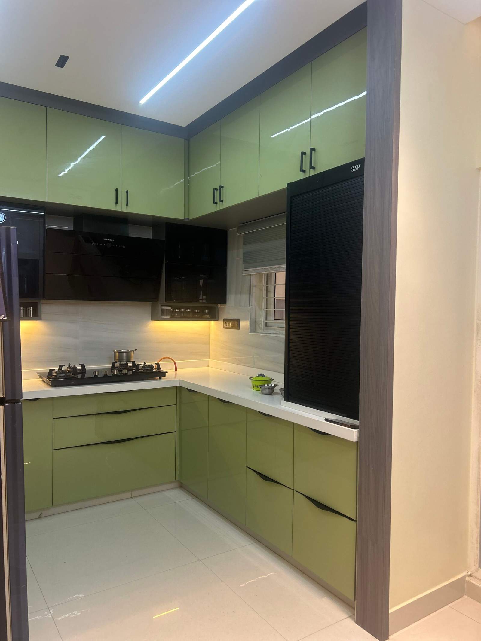 Green modular kitchen cabinet with rolling shutter storage in Bangalore home by Olangana Design’s.