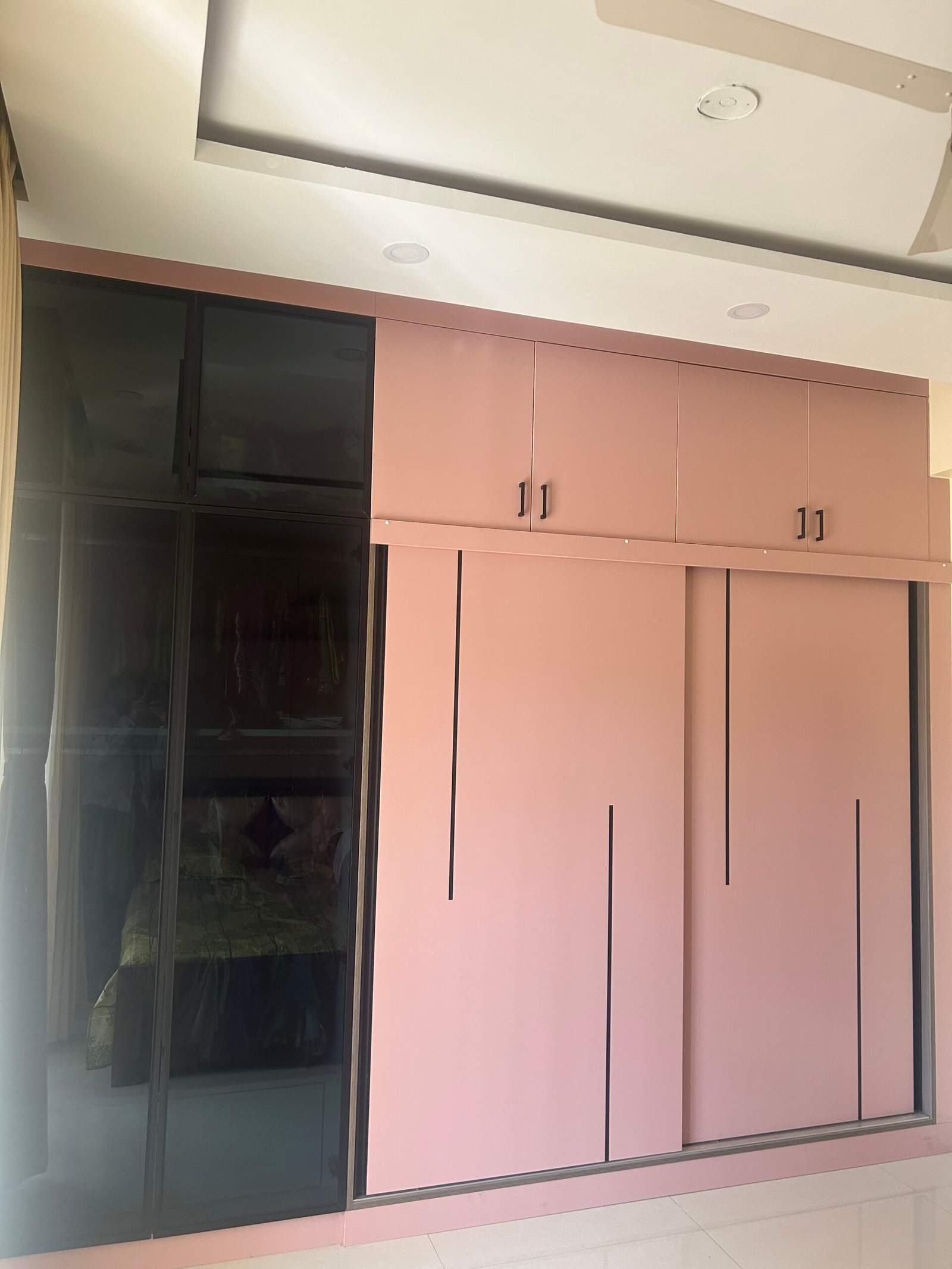 Stylish bedroom interior with pastel sliding wardrobe cabinets, wall mirror dressing unit, and foldable ironing table by Olangana Design’s.