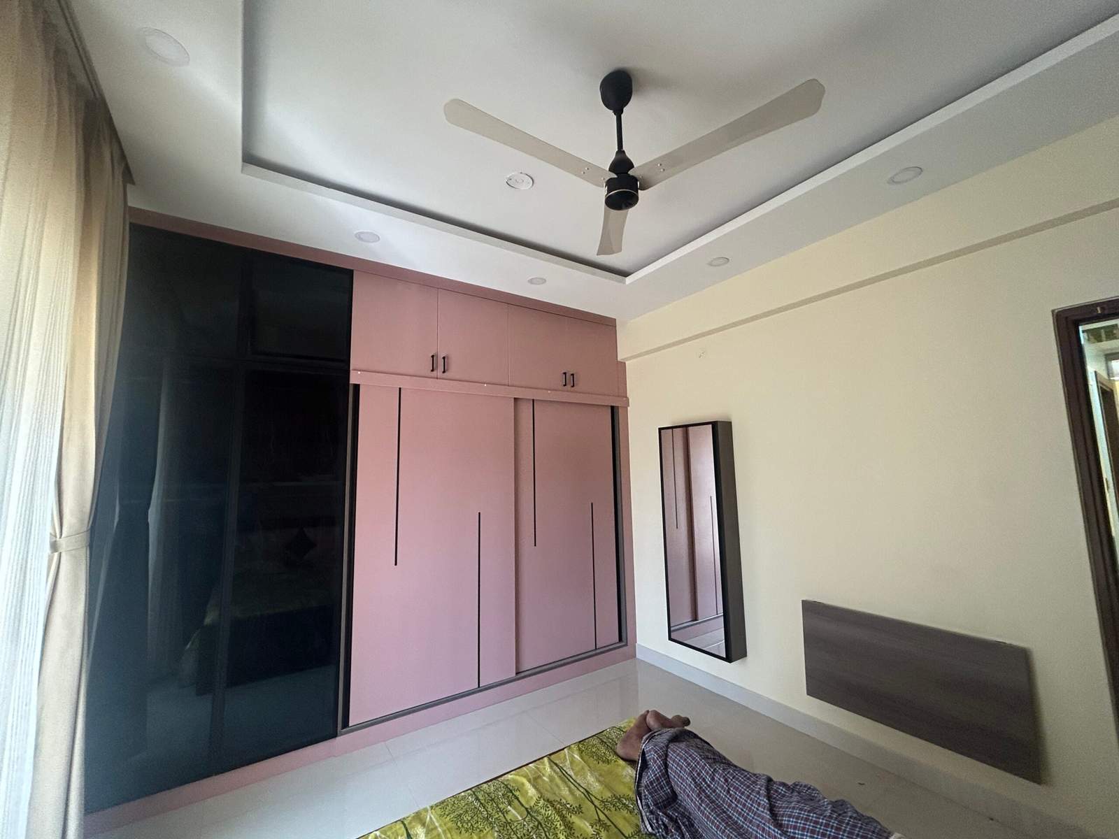 Contemporary bedroom design with sliding wardrobe storage, vertical dressing mirror, and wall-mounted ironing station by Olangana Design’s.