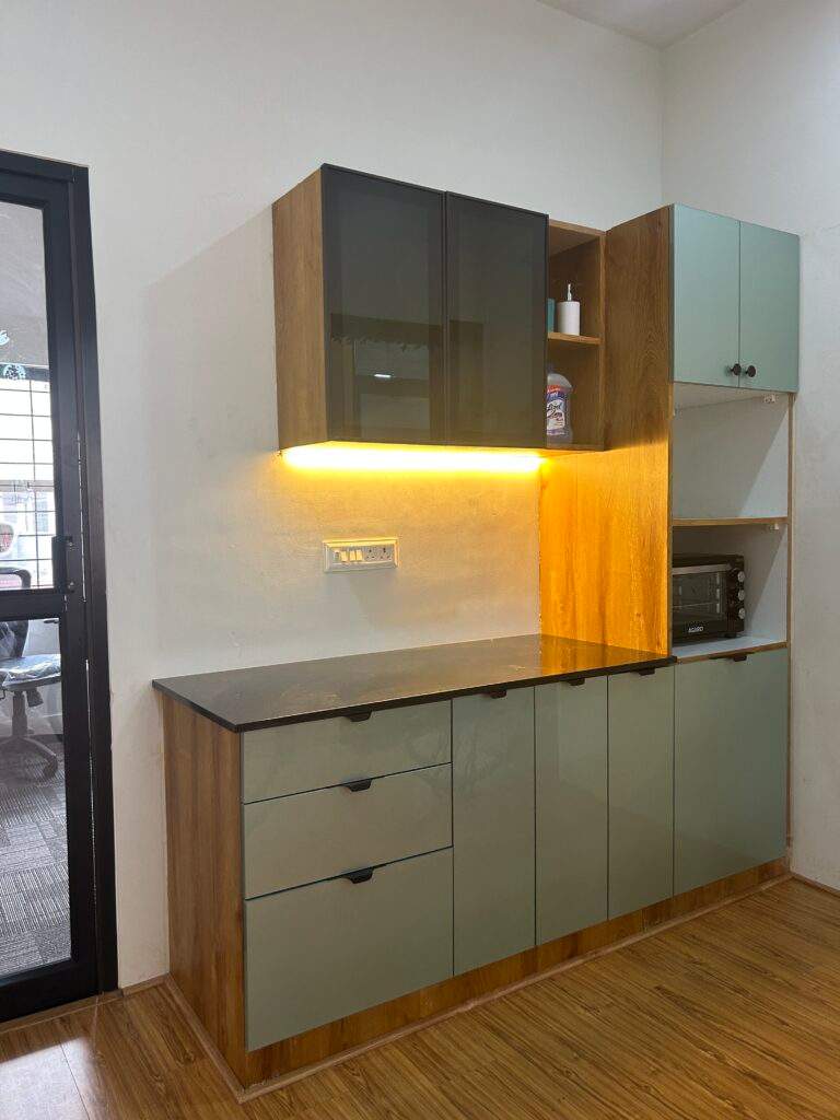 Olangana Design’s presents a modern office pantry interior in Bangalore with modular cabinets, storage drawers, warm LED lighting, and sleek countertop design.