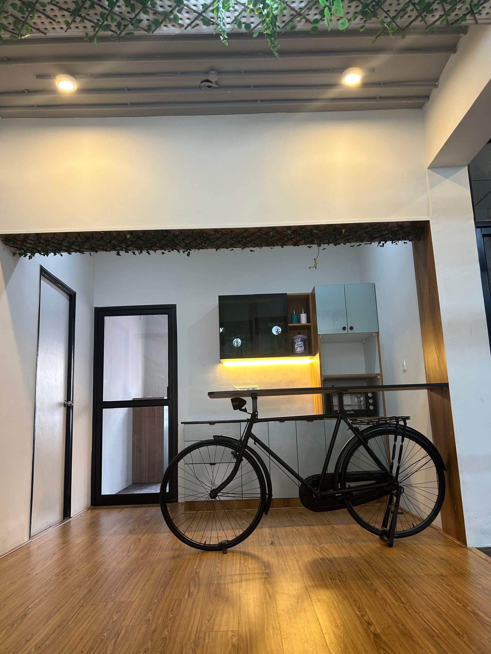 Modern office breakout space in Bangalore with wooden flooring, wall-mounted storage cabinets, and stylish cycle décor by Olangana Designs